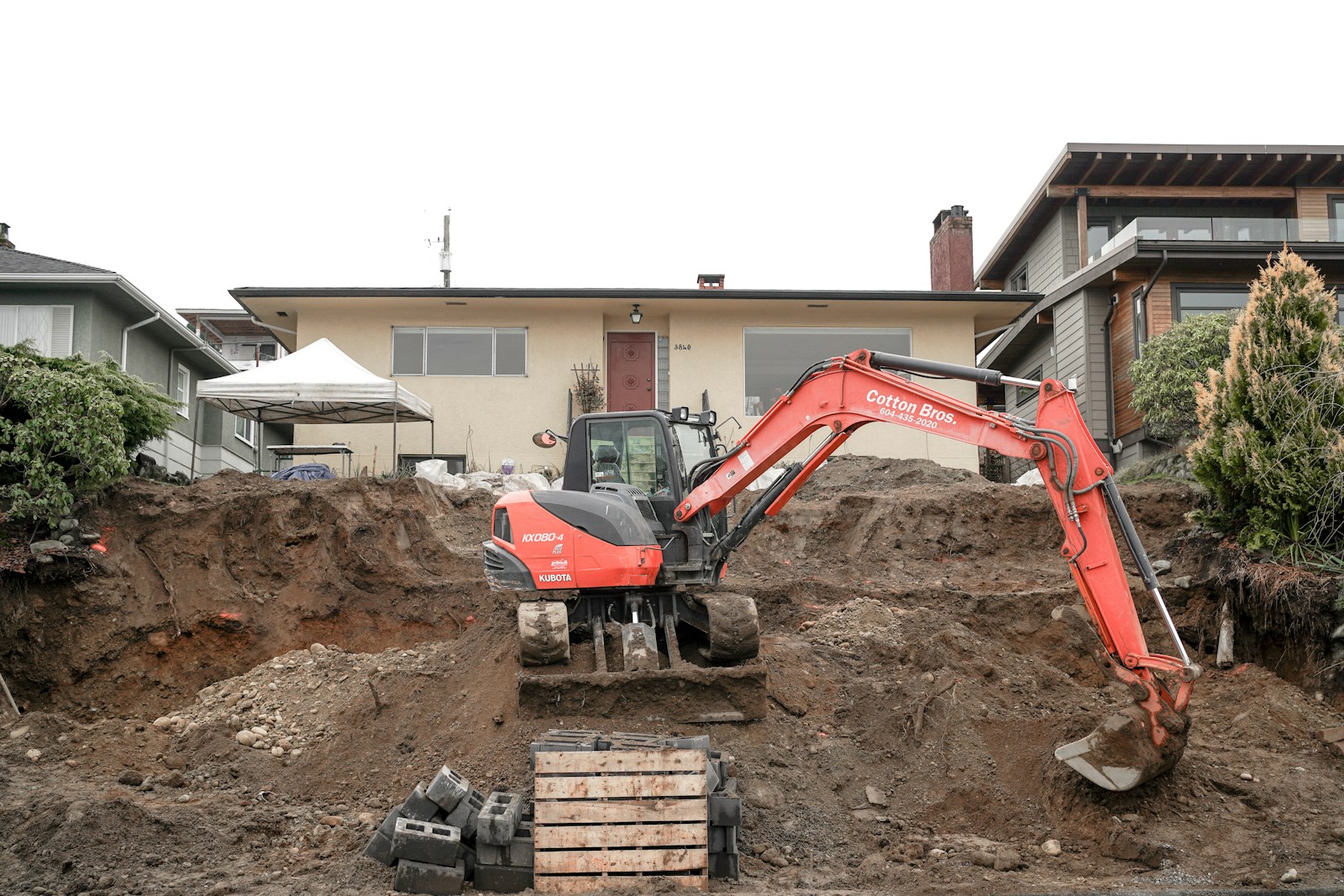 Excavator digging beside a house, illustrating site work for septic installation and repairs
